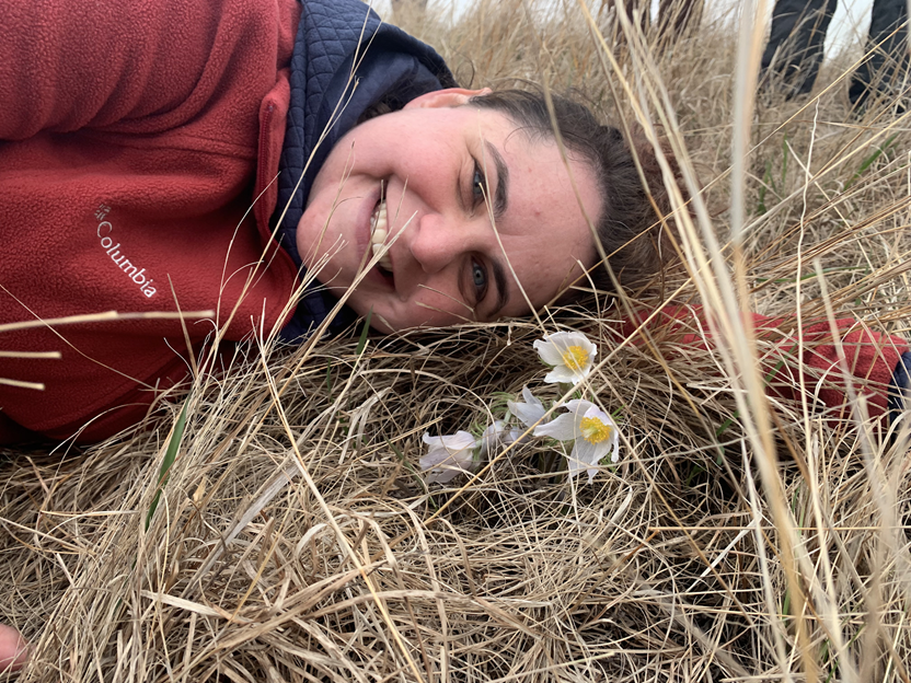 ARCS Scholar Alum Becky Barak lying in a field next to a flower